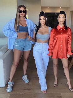 three women standing next to each other in front of a couch