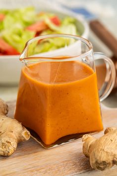 a glass cup filled with sauce next to some vegetables