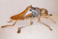 a metal and wood insect sculpture sitting on top of a white tablecloth covered floor