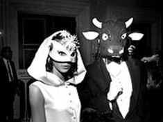 a man and woman dressed up in costumes standing next to each other with cows on their heads