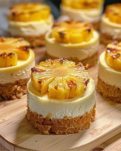 several desserts are arranged on a wooden tray with white frosting and pineapple topping