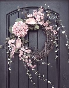 a wreath with pink flowers hanging on the front door