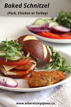 two plates filled with sandwiches and vegetables on top of a white table cloth next to each other