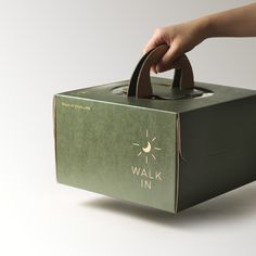 a person holding onto a green box with the word walk in on it and a brown handle