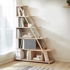 a bookshelf with several shelves in front of a window and a rug on the floor