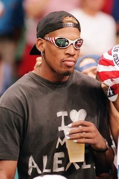 a man with sunglasses and an american flag on his head is drinking from a cup