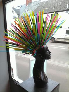 a sculpture of a woman's head with multicolored sticks sticking out of it