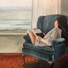 a painting of a woman sitting in a chair reading a book by the window, looking out at the ocean