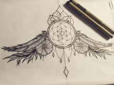 a drawing of a dream catcher with feathers on it and a pen next to it