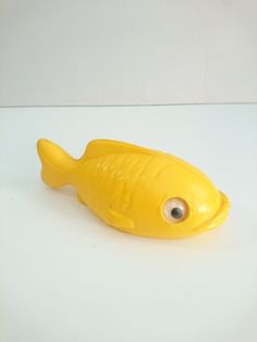 a yellow toy fish sitting on top of a white table