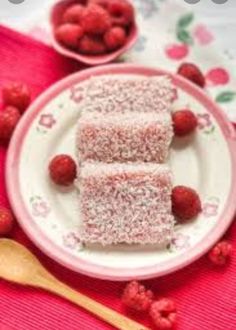 two pieces of cake on a plate with raspberries and strawberries in the background