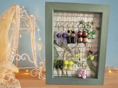 there is a shadow box with flowers in it and some beads hanging on the wall