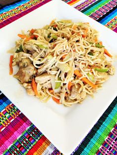 a white plate topped with food on top of a colorful table cloth next to a fork