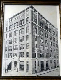 an old black and white photo of a tall building with windows on the top floor