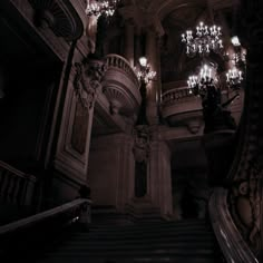 the chandeliers are hanging from the ceiling above the stairs in an old building