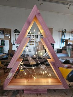 a wooden christmas tree sitting on top of a hard wood floor in a room filled with tools