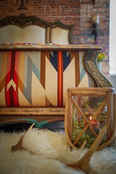 an upholstered bench with a lit candle in the center surrounded by pillows and rugs