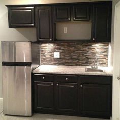 a kitchen with black cabinets and silver appliances