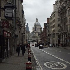 people are walking down the street in front of buildings and a domed building with a clock on it