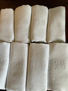 six folded towels with the word mom written in cursive font on them, sitting on a table