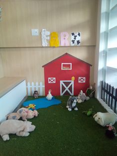 there are many stuffed animals on the grass in front of a red barn and fence