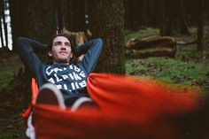 a man laying on the ground next to a tree with his hands behind his head