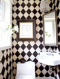 a bathroom with black and white checkered wallpaper, a toilet, sink and mirror