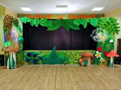 an indoor stage set up with mushrooms, plants and trees on the floor for a children's birthday party