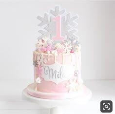 a pink cake with white frosting and flowers on top is decorated with a first birthday sign