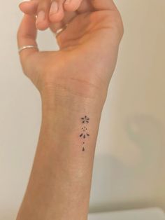 a woman's arm with a small tattoo on it that has flowers in the middle