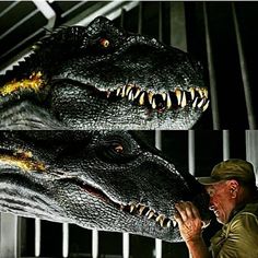 a man is touching the head of a large dinosaur with his mouth open and teeth out