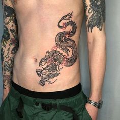 a man with tattoos on his stomach has a dragon tattoo on his side and chest