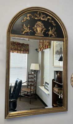 a mirror that is on the wall in front of a chair and table with a lamp