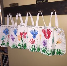 four handprinted bags hanging from a hook on a wall with the words happy mother's day written on them