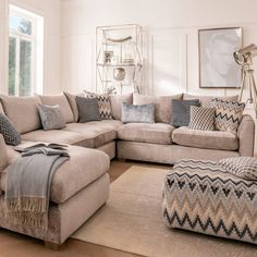 a living room filled with lots of furniture and pillows on top of a wooden floor