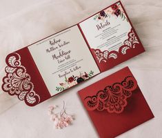 two red and white wedding cards on top of each other next to a pair of earrings