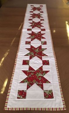 a long table runner with red and green stars on the top, sitting on a wooden surface