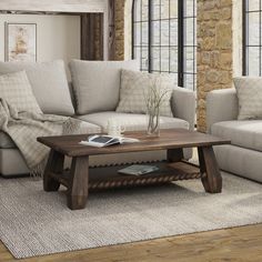 a living room with two couches and a coffee table in front of a brick wall