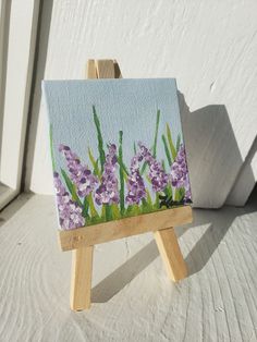 a small easel with purple flowers painted on it