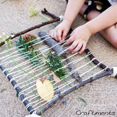 a child is playing with an old weaving frame made out of branches and twigs, while holding the string