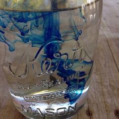 a glass jar filled with blue liquid on top of a wooden table