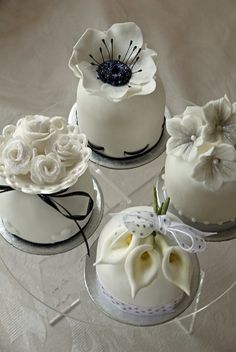 three cakes decorated with white flowers and ribbons