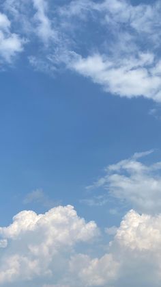 an airplane is flying high in the sky with white clouds behind it and blue skies above