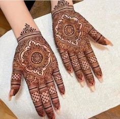 two hands with henna designs on them, one is showing it's intricate design