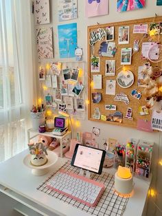 a white desk topped with a laptop computer next to a wall covered in pictures and magnets