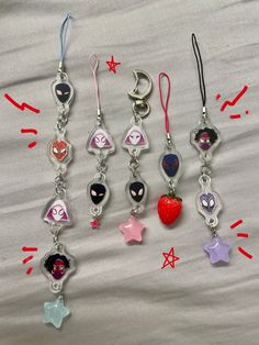 six different keychains with various designs on them sitting on a white sheet in front of red and blue confetti