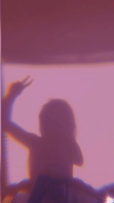 a blurry image of a person standing in front of a window with their hand up