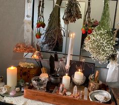 a table with candles, flowers and other items in front of two mirrors on the wall