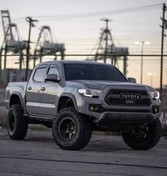 a gray toyota pickup truck parked in front of a chain link fence and power lines