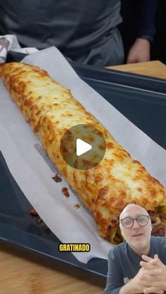 a man sitting in front of a large piece of pizza